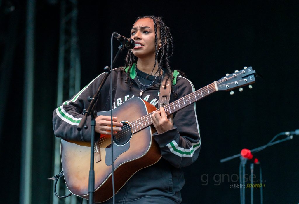 Amie Blu singing during a rain-soaked Wider Than Pictures show